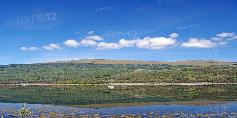 A clear lake reflects the surrounding mountains and cloudy sky, Caledonian Canal, Fort William, Scotland, United Kingdom