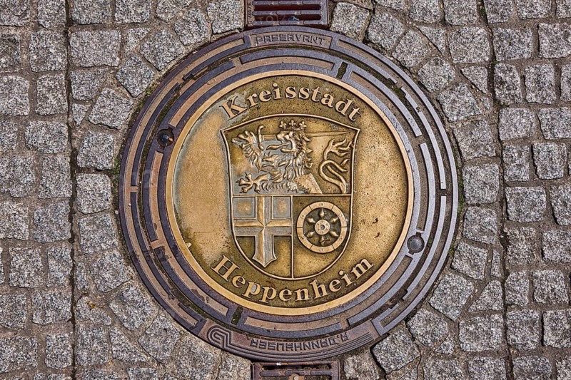 Manhole cover, district town of Heppenheim, golden, pavement made of paving stones, rain gutter, Heppenheim, Odenwald, Bergstrasse district, Hesse, Germany