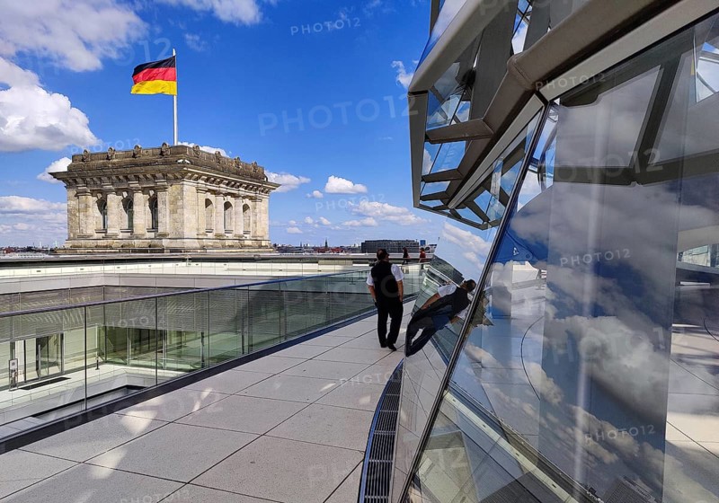 Viewing platform with a German flag in the wind on one of the corner towers and the Reichstag dome, government district, Berlin, Germany