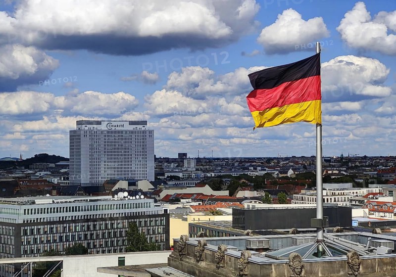 View from the Reichstag dome of a German flag in the wind with the Charité bed tower, Reichstag building, Berlin, Germany