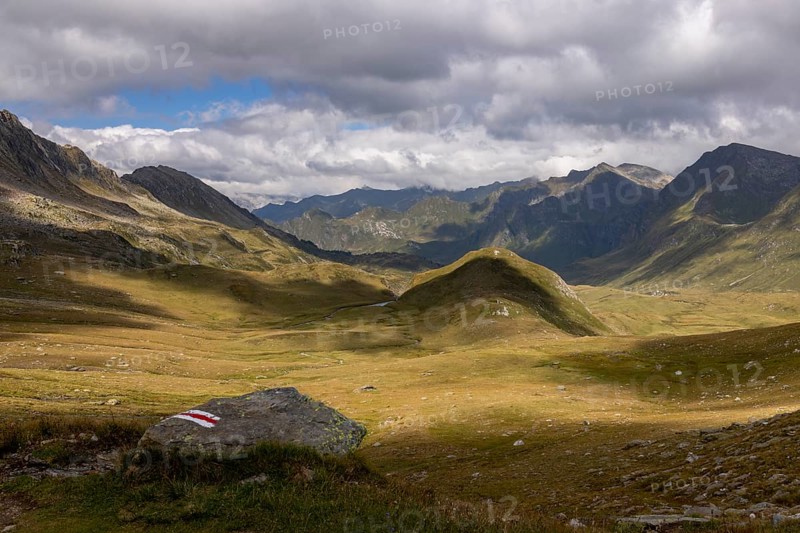 View from Passo del Sole in Alpe Carorescio with Piano Grande plateau and hiking trail marker, Quinto, Ticino, Switzerland
