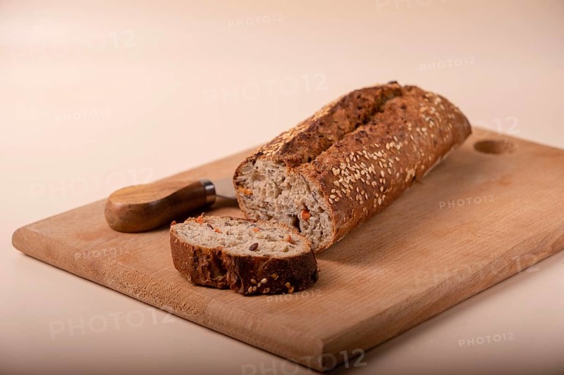 Slices of whole grain bread with carrots and seeds on wooden board on beige background, copy space