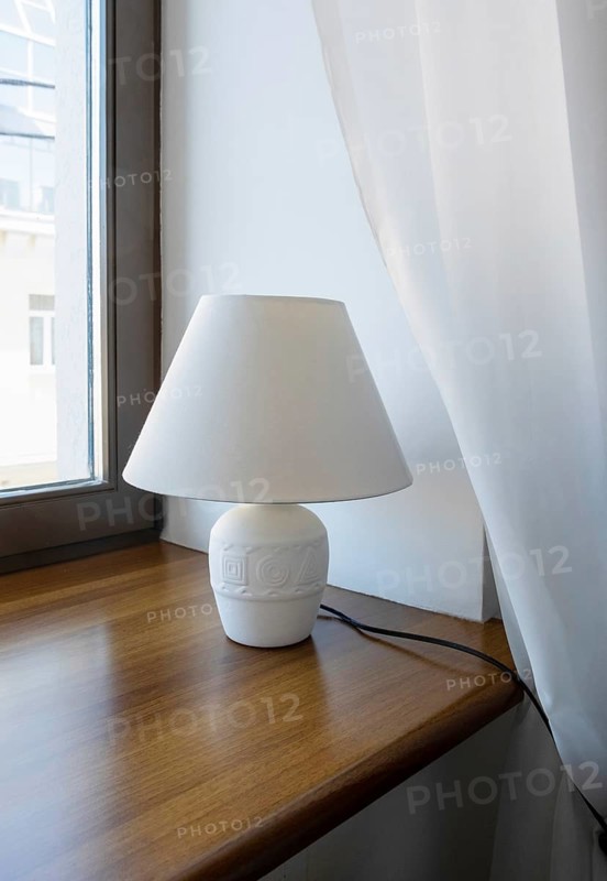 A table lamp, a night light stands on the windowsill in a hotel