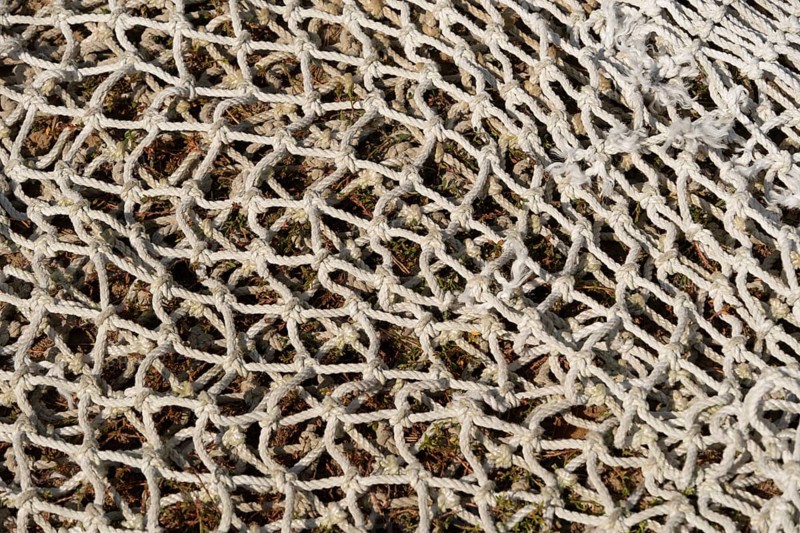 Fishing net lying on the ground, textured background