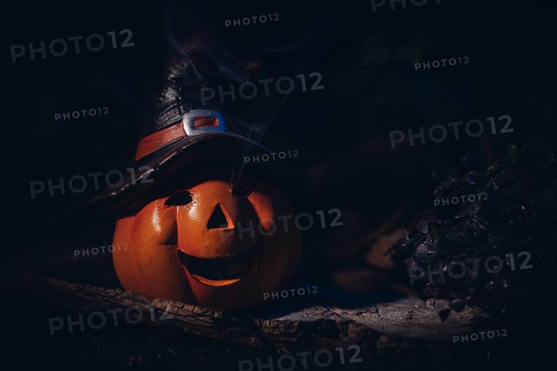 Pumpkin lantern with witch's hat in a spooky, dark setting