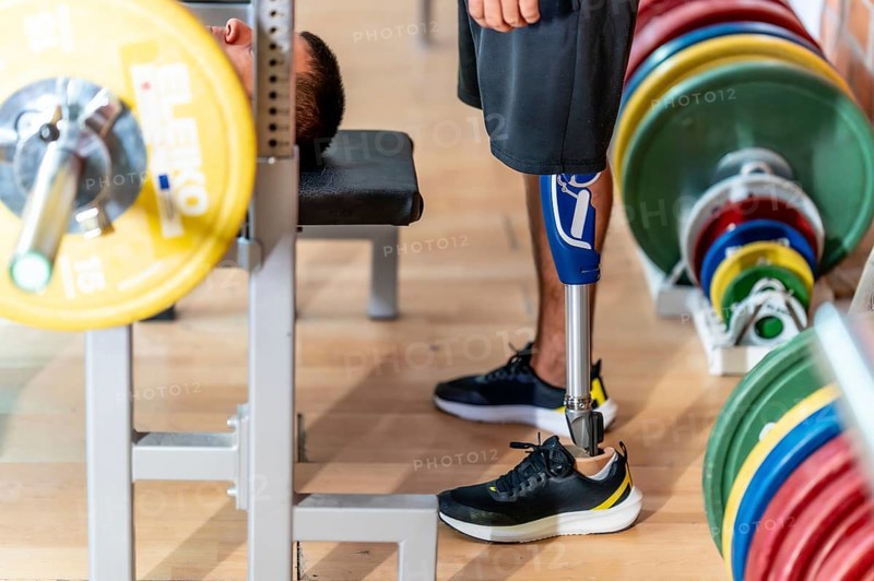 Adaptive athlete with a prosthetic leg doing weightlifting exercises on a gym bench, demonstrating strength, determination, and overcoming physical challenges through sport and fitness