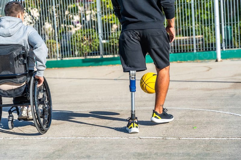Young men with disabilities enjoying a basketball game together on an outdoor court, embracing sport, friendship, and inclusion while demonstrating active lifestyles