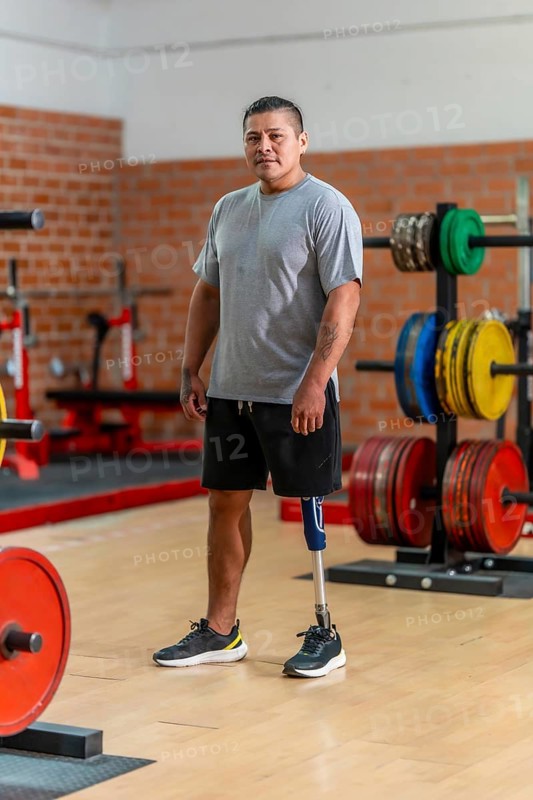 Male amputee athlete standing confidently in a gym, showcasing his prosthetic leg and symbolizing resilience, fitness, and overcoming challenges in a modern and active lifestyle