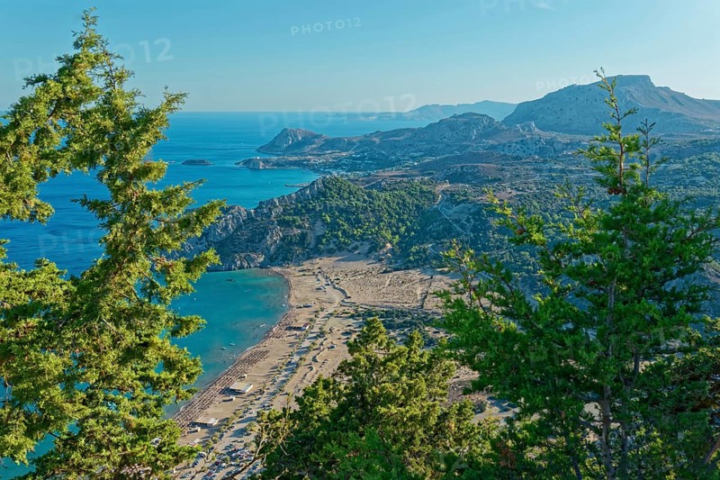 View of the Tsambika sandy beach, with mountains and blue sea, framed by green trees, Church of the Virgin Mary Tsambika (Kyra Psili), Archangelos, Rhodes Island, Greece