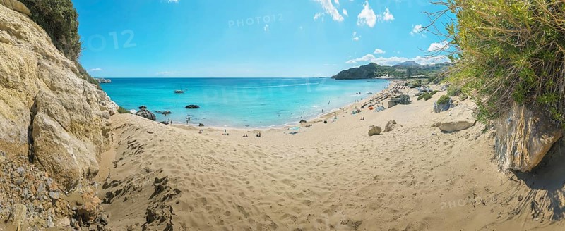 A quiet place on Tsambika sandy beach of Tsambika with clear blue sea and rocks under a sunny sky, ideal for relaxation, Tsambika beach, Archaggelos, Rhodes island, Greece