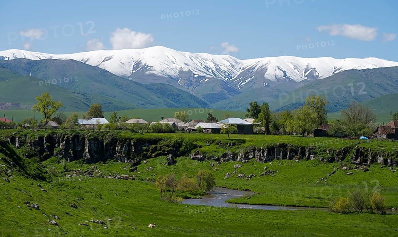 A village in a green landscape with snow-capped mountains in the background, Saratovka, Lesser Caucasus, Lorikeet Province, Armenia