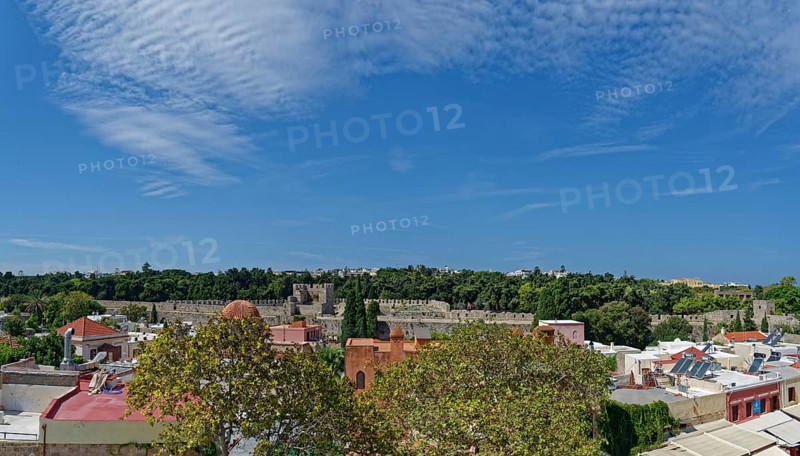 View of a historic old town with many trees and traditional buildings under a clear blue sky, Medieval Town of Rhodes, Rhodes Island, Greece