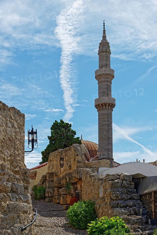 A minaret with a blue sky and ancient walls in a tranquil, historic setting, Suleiman Mosque, Medieval Town of Rhodes, Rhodes Island, Greece