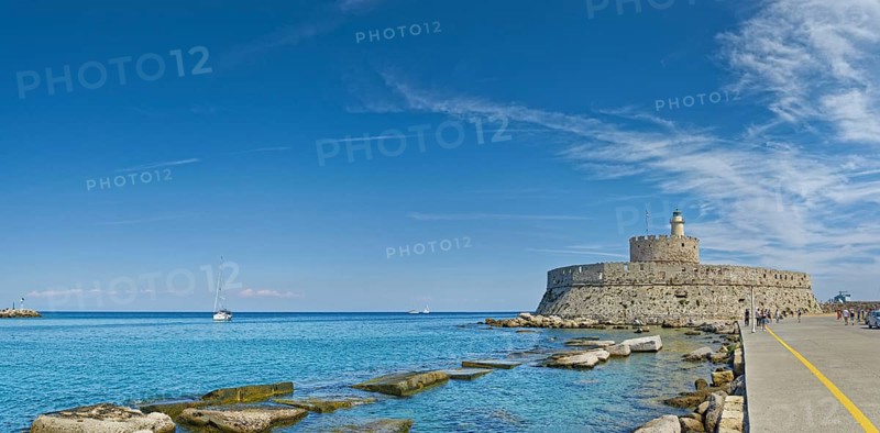 Fort of Saint Nikolaos stretches along the coast in the bright sunshine, Mandraki harbour, Medieval Town of Rhodes, Rhodes Island, Greece