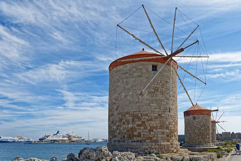 Historic windmills of Rhodes at Mandraki harbour with ships in the background, Mandraki harbour, Medieval town of Rhodes, Rhodes island, Greece