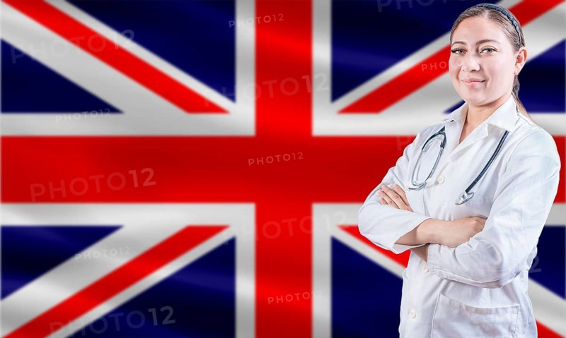 Female doctor on United Kingdom flag. Doctor with crossed arms on United Kingdom flag. United Kingdom health and care concept