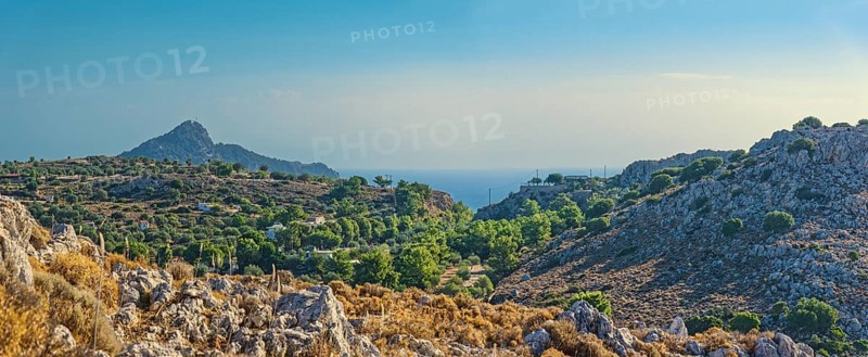 Hilly landscape near Stegna with green vegetation, sea view and blue sky, Stegna, Archangelos, Rhodes Island, Greece