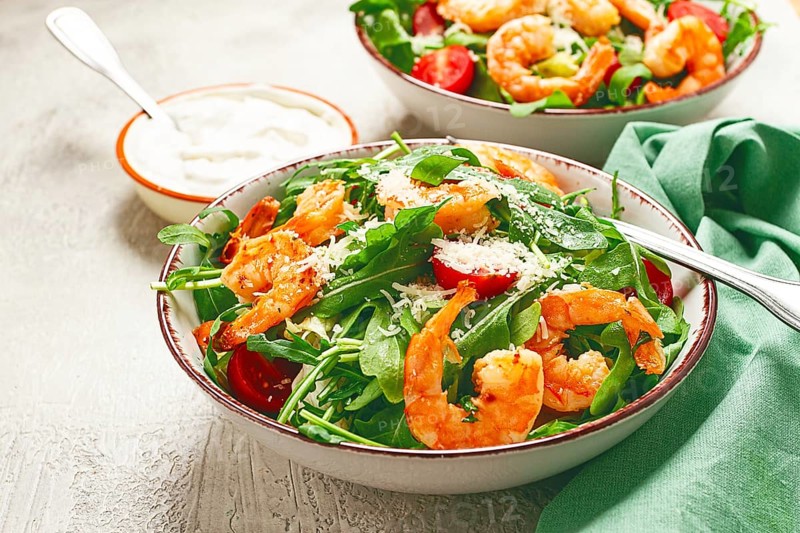 Two bowls of shrimp salad, arugula and cherry tomatoes, with parmesan cheese, healthy food