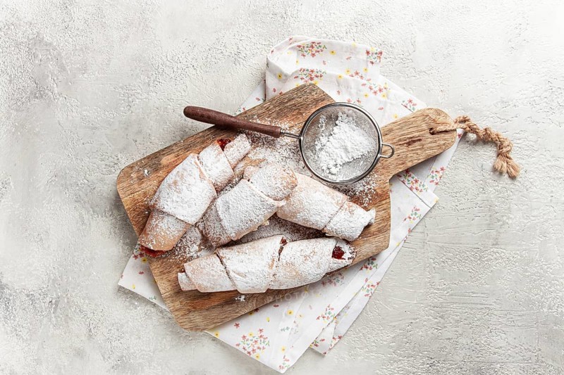 Bagels with filling, sweet pastries, sprinkled with powdered sugar, on a wooden board, dessert, breakfast