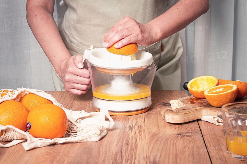 Preparation of freshly squeezed orange juice, using a juicer, in a cozy kitchen setting