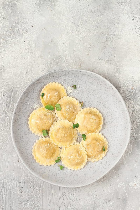 Fresh, ravioli with cheese, and microgreens, on a light plate, top view, no people