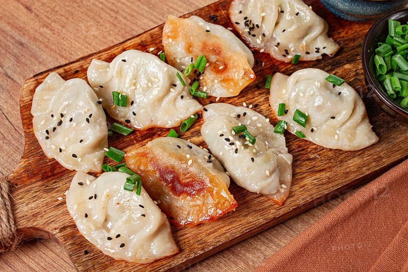 Gyoza Japanese dumplings, fried, with sauce, with green onion and sesame seeds, no people, selective focus