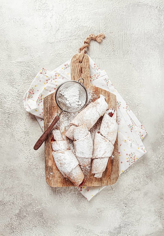 Bagels with filling, sweet pastries, sprinkled with powdered sugar, on a wooden board, dessert, breakfast