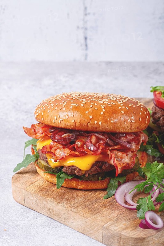 Burger with beef and bacon, with arugula and caramelized onions, pickles, sauce, homemade, no people