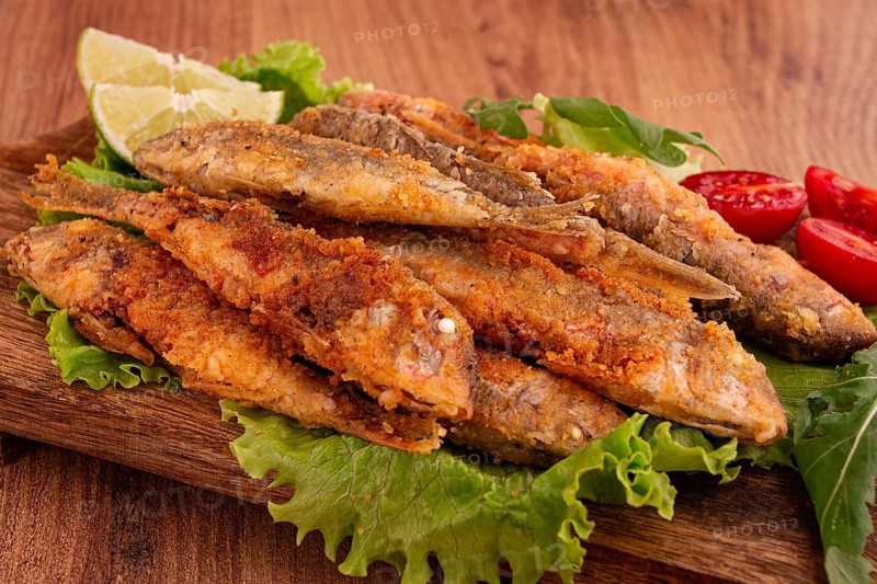 Fried crispy red mullet fish, on a wooden chopping board, with lime, no people