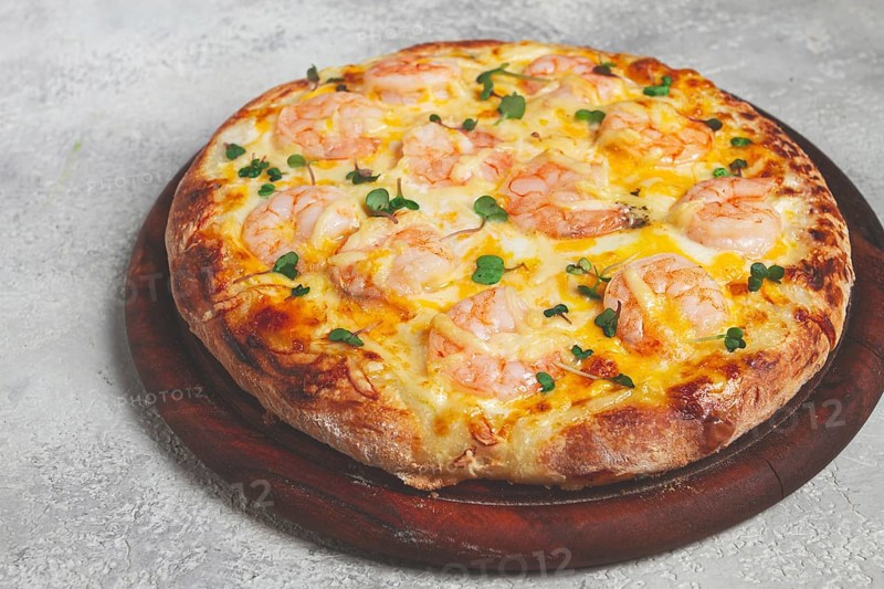 Four cheese pizza with shrimp and fresh microgreens, served on a wooden board, homemade, no people