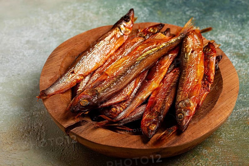Cold smoked capelin, on a wooden bowl, top view, no people