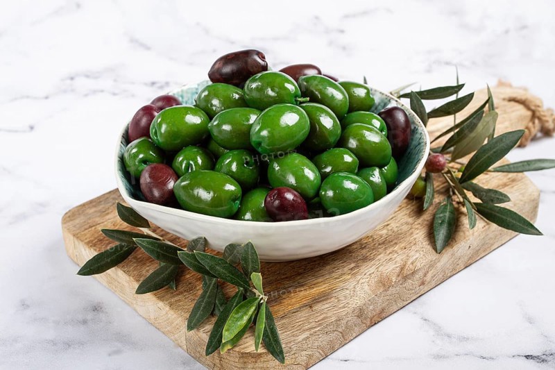 Chalkidiki olives, classic Greek green olives, in a bowl on a cutting board, top view, without people