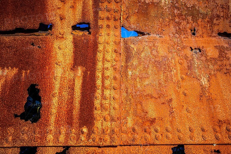 The rough texture of heavily corroded iron plates on the hull of. derelict ship. British Columbia, Canada