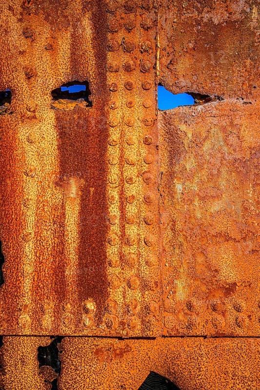 The rough texture of heavily corroded iron plates on the hull of. derelict ship. British Columbia, Canada