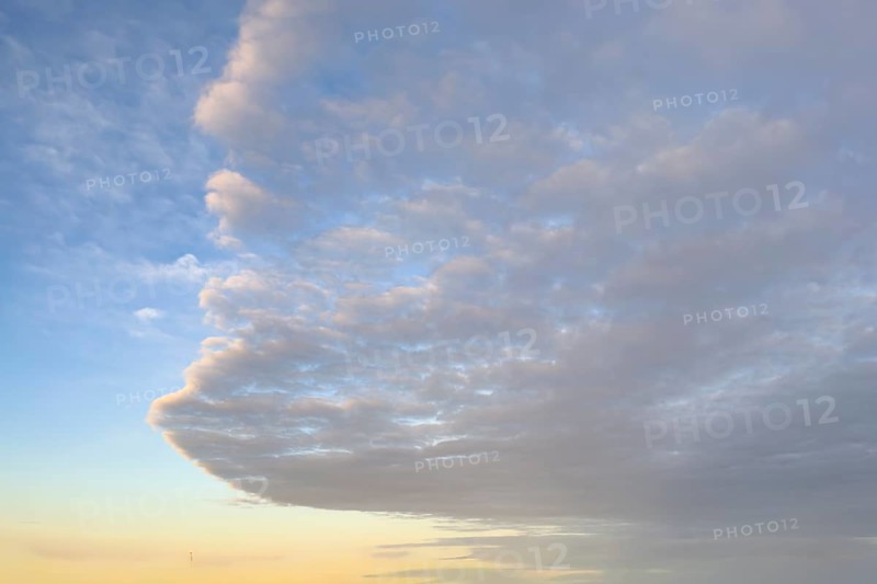 Cloud front with stratocumulus clouds below Stratocumulus clouds with dynamic arc shape above Altocumulus under blue sky Cluster layer clouds below in the background golden evening sky shortly in front of dusk, international