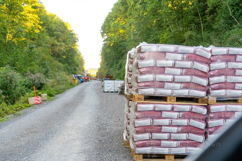 Stacked pallets of building materials line a gravel road in the forest, Hermann Hessebahn construction site, Calw, Germany