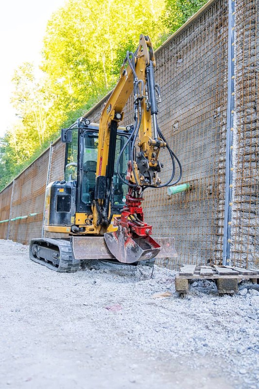 Mini excavator next to a metal mesh construction wall on a building site, Hermann Hessebahn construction site, Calw, Germany