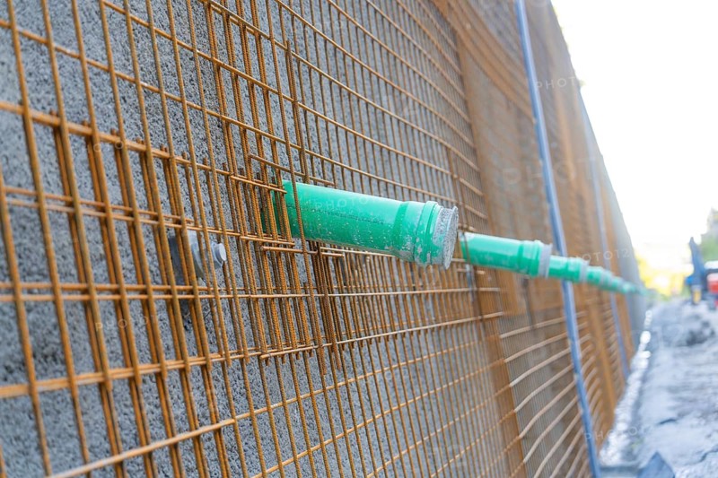 Metal grid with green pipes in front of a concrete wall on a construction site, Hermann Hessebahn construction site, Calw, Germany