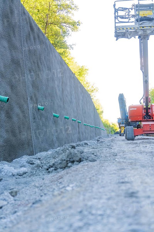 Concrete wall along a road with exposed earth and equipment on a construction site, Hermann Hessebahn construction site, Calw, Germany