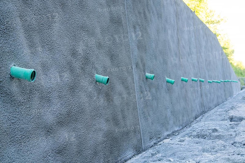 A row of green pipes protrudes from a reinforced concrete wall on a construction site, Hermann Hessebahn construction site, Calw, Germany