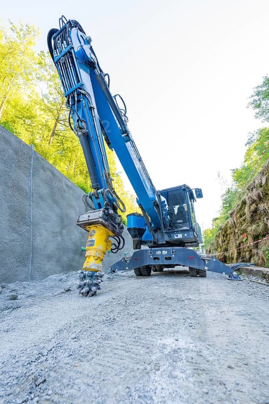 Blue crane with drill head on construction site on concrete wall, surrounded by nature, Hermann Hessebahn construction site, Calw, Germany