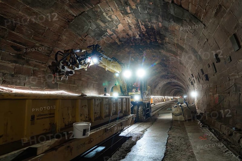Tunnel with rail construction work and strongly illuminated machines, construction of the Hermann Hesse railway, Calw, Black Forest, Germany