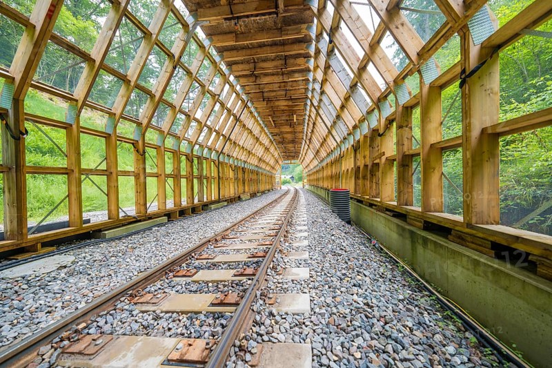 An open tunnel with a view of a green environment and an illuminated interior, construction of the Hermann Hesse railway, Calw, Black Forest, Germany