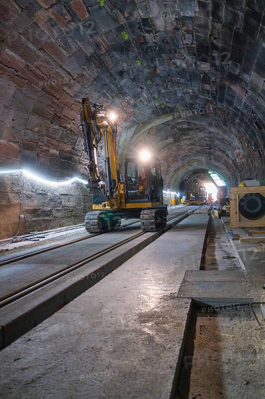 An excavator in an illuminated tunnel on rails, with a depth of perspective in the scene, construction of the Hermann Hesse railway, Calw, Black Forest, Germany
