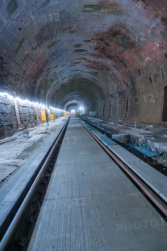 A long, illuminated tunnel with tracks and a deep perspective. The walls appear structured, construction of the Hermann Hesse railway, Calw, Black Forest, Germany