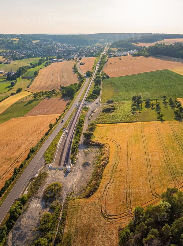 Fields and tracks, running parallel to a road, surrounded by trees, with a view of a distant village, construction of the Hermann Hesse railway, Calw, Black Forest, Germany