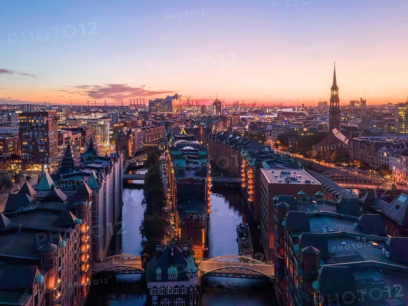 Aerial view of Hamburg's Speicherstadt warehouse district at sunset with a view of the moated castle, the Poggenmühlenbrücke bridge and the Elbphilharmonie concert hall and St Michael's Church in the background, Hamburg, Germany