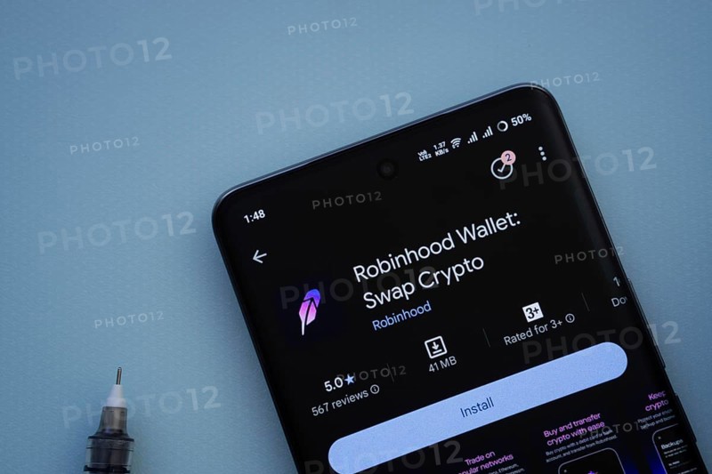 Dhaka, Bangladesh- 29 May 2025: On a blue surface, a smartphone displays the Robinhood Wallet app within the Google Play Store