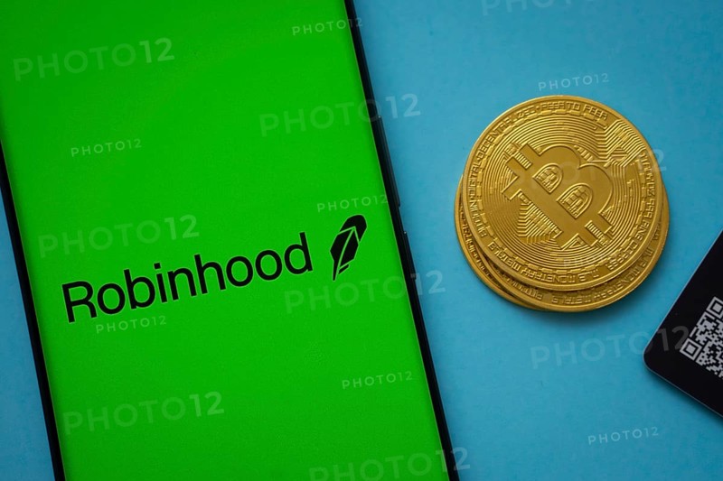 Dhaka, Bangladesh- 26 Aug 2025: Robinhood logo on smartphone screen near Bitcoin coin and QR code on blue background