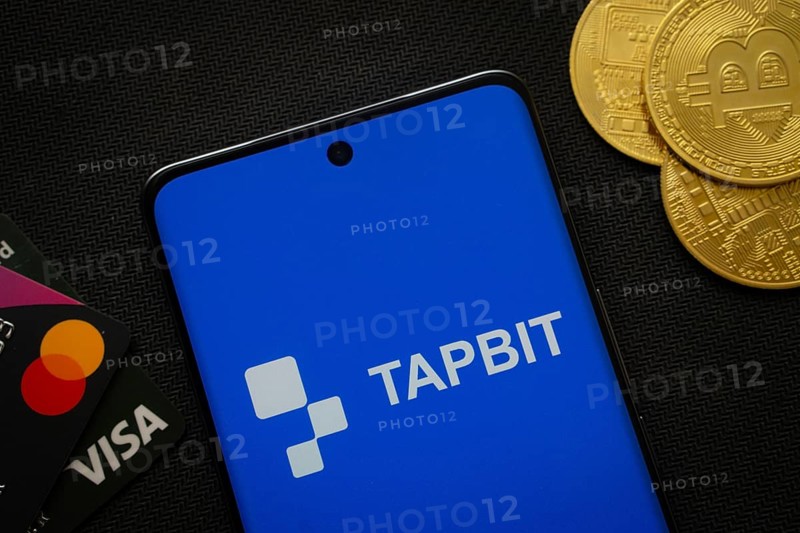 Dhaka, Bangladesh- 20 Sep 2025: Smartphone displaying Tapbit logo surrounded by Bitcoin coins and payment cards